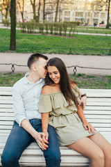 Happy young couple in love sitting on a park bench and hugging