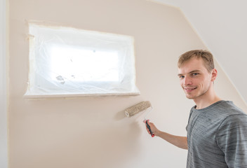 Mann streicht Zimmerwand