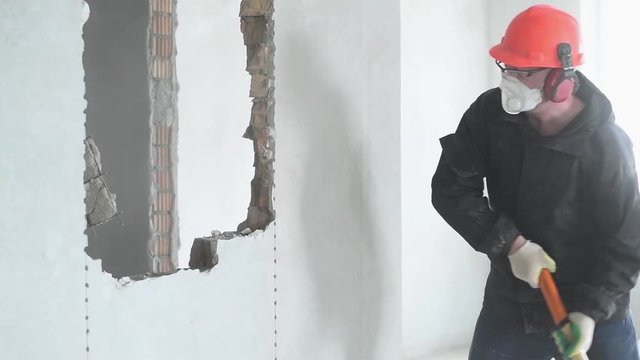 demolition work and rearrangement. worker with sledgehammer destroying wall