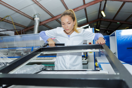 female worker inspecting window frames at factory
