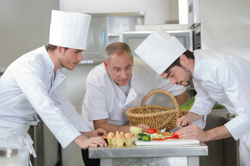 chief chef watching his assistant garnishing a dish