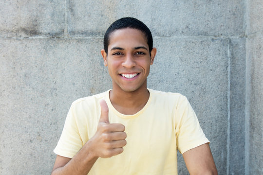 Laughing egyptian young adult man showing thumb up