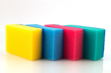 Поролоновые чистящие губки разных цветов для удаления с бытовых поверхностей загрязнений, расположенные в один ряд зигзагом.