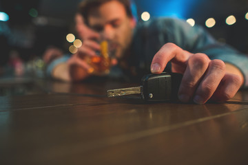 Dangerous choice. Close up male hand keeping switch-key in hand while tasting alcohol in pub