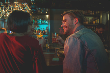 Side view cheerful female talking with happy man. Glad couple drinking alcohol beverage in bar concept