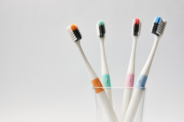 Colorful Toothbrushes in glass on white background, dental and oral care concept