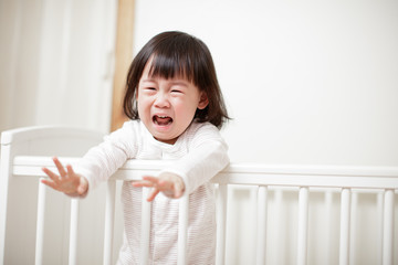 Crying Baby girl in cot bed