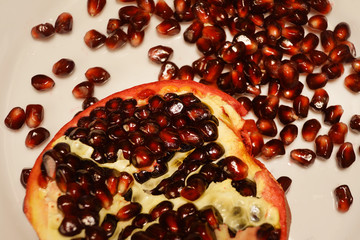 Pomegranate and pomegranate seeds on a plate.