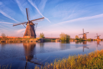Scenic sunset landscape with windmill, blue sky and reflection in the water. Traditional dutch...