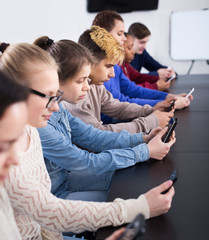 Fellow students playing with their smartphones