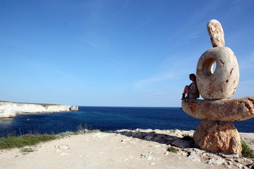 a girl on a stone by the sea
