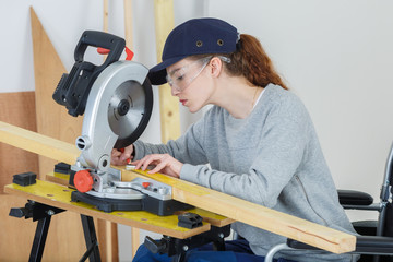 young female carpenter using a circular saw