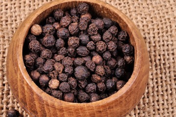 pepper not ground in a wooden bowl on a ragged background.