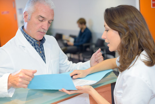 Doctor Talking To Secretary At Reception