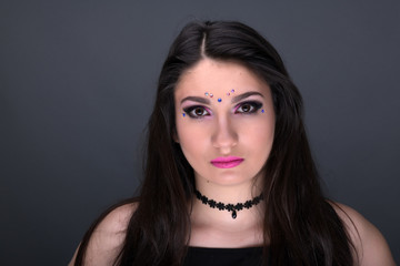 Close up face. Young arabic woman in black sexy dress, isolated on gray background