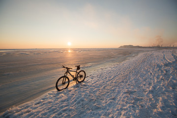Mountain bike stay in snow near frozen sea or lake. Winter bicycle exploitation and maintenance....