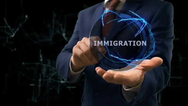 Businessman shows concept hologram Immigration on his hand. Man in business suit with future technology screen and modern cosmic background