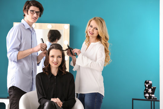 Professional hairdressers working with client in salon