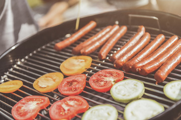 Bon appetite. Close up of tasty sausages and vegetables on grill