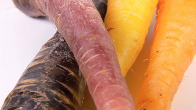 A bunch of carrots (not the usual variety, yellow and violet colors) on a rotating surface. Above close-up shot.
