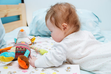 The infant plays with a Fox toy on the bed.