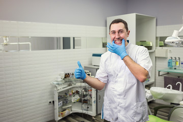 Male dentist standing over medical office background. Healthcare, profession, stomatology and medicine concept