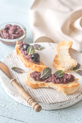 Toasts with black olive pate on the wooden board