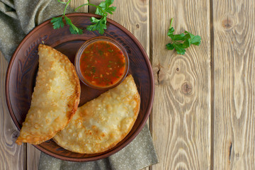 chebureks with tomato sauce on wooden background