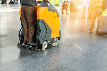 Man driving professional floor cleaning machine at airport or railway station.  Floor care and cleaning service agency
