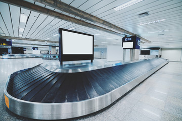 Wide-angle view of a modern baggage conveyor belt in a contemporary airport terminal: multiple...