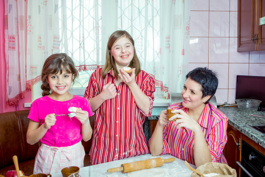Mom teaching her two daughters cooking on the kitchen.