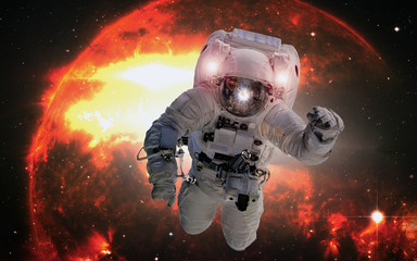 Astronaut in outer space on the orange giant star background. Elements of this image furnished by...