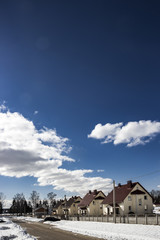 sunny day street snow lies with cottages car costs road blue sky clouds background vertical 