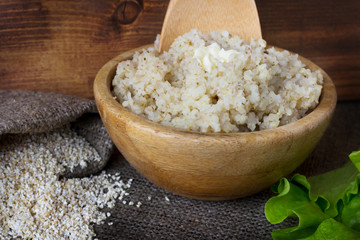 Barley groats in a bowl. A baggie of dry cereal and green salad leaves on rustic background.