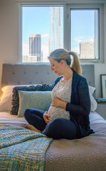 Pregnant woman touching her belly in bed