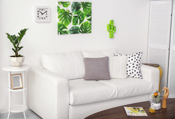 Stylish modern room interior with picture of tropical leaves on wall