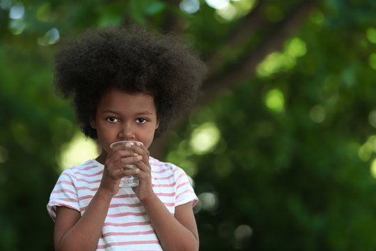 African American child drinking water outdoors. Water scarcity concept