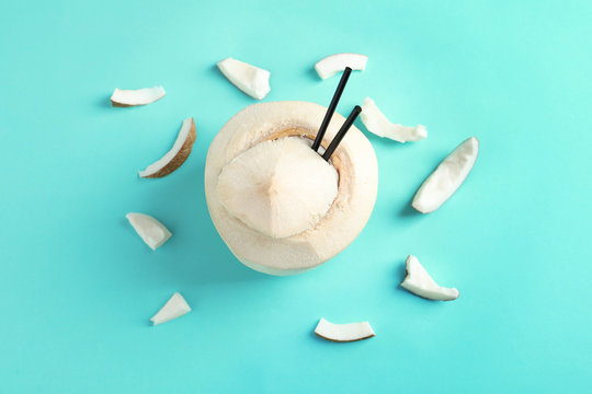 Fresh coconut drink in nut on color background