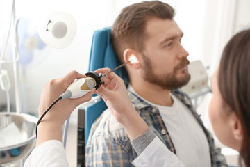 Otolaryngologist examining man's ear with ENT telescope in hospital. Hearing problem