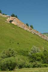 Unique green mountain landscape with high rocky mountains and blue sky. Geological section, fault in distance. Background from unimaginable rocks.