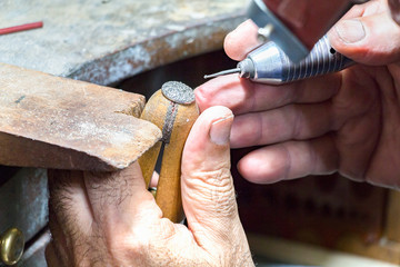 Jeweler engraving diamonds on a ring.
