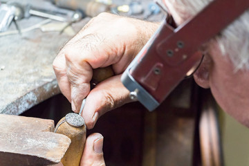 Jeweler engraving diamonds on a ring.