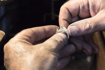 Jeweler hands close up with a silver ring.