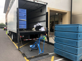 Bulk laundry delivery service, large carts on ramp of truck for distribution.