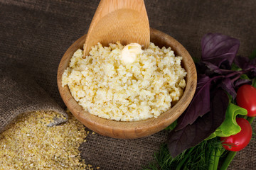 Wheat grits in a wooden bowl, baggie of dry cereal and vegetables. Healthy food.