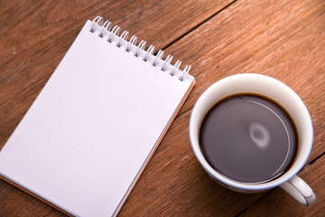 Coffee cup top view and notebook on wooden vintage table background