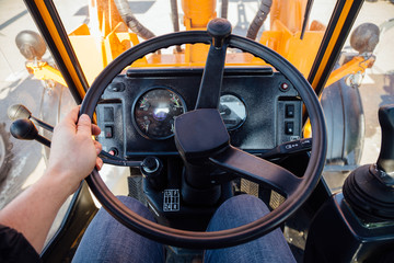 Inside modern tractor. Steering wheel. View from work place.