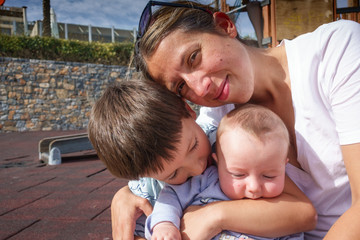 Fototapeta na wymiar Mother with sons at playground, Greece