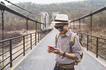 Young man traveller using mobile phone on bridge.