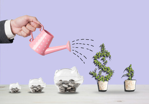 Transparent piggy bank filled with coins on wood background.Saving investment colorful concept.Watering can and money growth drawn concept for business investment, savings and making money.